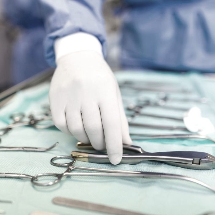 Surgeon picking up surgical tool from tray surgeon is preparing for surgery in operating room he is in a hospital